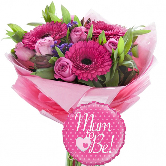 A vibrant pink new baby bouquet is displayed against a simple white background, allowing each colour and texture to stand out as if viewed in the soft daylight of a Cranford living room. Dominating the design are several large fuchsia gerbera daisies, their petals radiating in perfectly even rings from deep, dark centres that lend a sense of focus and visual drama. Nestled between and around them are pastel pink roses, some tightly budded with smooth outer petals, others beginning to unfurl into layered spirals that give the bouquet a feeling of gentle movement and growth. Fine clusters of purple filler flowers, most likely statice or limonium, are worked through the arrangement, their small, papery blooms providing a light, cloud-like veil that contrasts attractively with the bold gerberas and plush roses. The blooms are supported by an assortment of fresh green foliage: slim, elongated leaves arc outward, while smaller, broader leaves sit closer to the stems, adding structure and framing the flowers in a halo of greenery. The bouquet is tied and wrapped at the base in layers of pink tissue paper, some bright and some more muted, which are ruffled and fanned to create a soft, voluminous collar around the stems. A clear cellophane covering surrounds the outer layer, adding protection and a gentle glossy sheen. In front, attached at the base, sits a round foil balloon in vivid pink with a gently scalloped edge. The balloon is patterned with neat white polka dots and features the words Mum to Be! across the centre in flowing white script, with a small double-heart motif beneath the text. Together, the flowers and balloon create a joyful, affectionate arrangement, perfect for marking pregnancy announcements, baby showers, or welcoming an expectant mother home in Cranford.