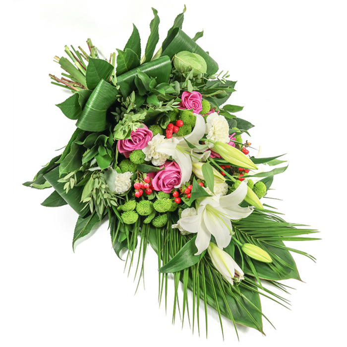 Set against a crisp white canvas, this sophisticated elongated funeral spray pays homage to Cranford's sense of community and tranquility. The diagonal line-flowing from upper left to lower right-leads the gaze across ivory oriental lilies, their open flowers exuding subtle perfume, while buds wait with promise. Punctuating the lilies are clusters of vibrant pink roses at varying stages of bloom, their richness evoking profound remembrance and celebration of life, reminiscent of the serene moments found in Cranford Park. Freshness bursts forth with playful button-like, lime-green chrysanthemums and plump, scarlet hypericum berries that shimmer within the greenery. White spray carnations nestle between the larger blossoms, softening transitions and amplifying the bouquet's lush fullness. Surrounding everything, diverse greenery-broad folded leaves for structure, delicate sprays, and gracefully trailing palm fronds-creates a dynamic yet balanced frame. Subtle daylight accentuates each hue and petal texture, capturing the arrangement's thoughtful balance between tradition and contemporary design. This floral tribute, as offered by Cranford Flowers, is an expression of compassion, dignity, and solace, making it an ideal choice for funerals, memorials, or condolence gifts within the Cranford area.