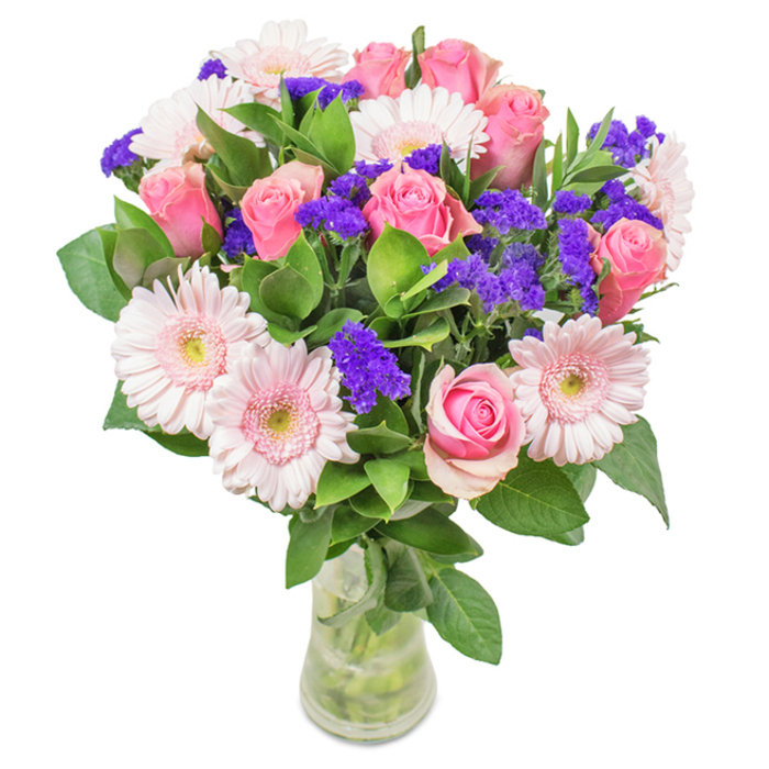 A meticulously composed bouquet, presented in a pristine glass vase, captures the artistry of local Crane Valley floristry. At its centre, 7 to 9 medium pink roses display a spectrum of petal stages-from delicate buds to half-open, spiraling blooms-offering a classic romance that sits beautifully against about 5 to 7 pale pink gerbera daisies. Each gerbera showcases large, rounded heads with radiant petals and almost white, gentle centres, reminiscent of Cranford's tranquil gardens. Vivid clusters of purple statice or limonium punctuate the arrangement, adding captivating texture and a pop of vibrant colour, much like the wildflower patches scattered along Cranford's streets. Lush, forest-green foliage spills beneath, lending a sense of natural abundance and breathing in scents of freshly cut stems. The transparent vase, stems visible and elegantly arranged in clean water, completes the scene-a tangible promise of freshness, ready for thoughtful delivery to a neighbour near Heston Road or for brightening a Sunbury Crescent home. Altogether, the bouquet is suitable for birthdays, anniversaries, Mother's Day, or as a welcoming touch of sophistication in a Cranford office, echoing the feeling of joy, affection, and community pride.